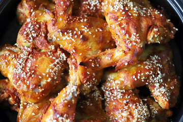 Selective focus. Appetizing buffalo wings in a pan. Baked chicken wings with sesame seeds.