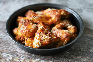 Selective focus. Appetizing buffalo wings in a pan. Baked chicken wings with sesame seeds.