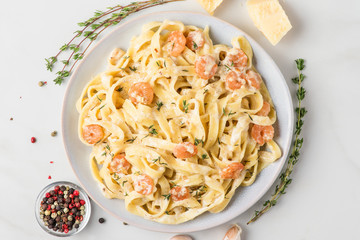 Pasta with shrimps, creamy sauce, parmesan cheese and thyme on a plate. Mediterranean fettuccine with seafood