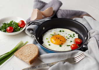 Fried egg with tomato and green onion in frying pan, tasty breakfast