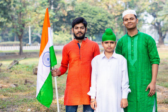 Three kids and young boys of different age and different religion hearing tricolor dress and holding Indian National flag. Indian kids celebrating Republic or Independence day of India.  - Powered by Adobe
