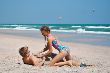 Fototapeta na wymiar Brother and sister playing on the beach. Happy children of the sea
