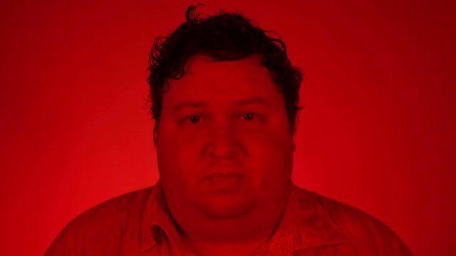 Portrait nervous afraid stressed young man feels awkward looking away sideway anxiously craving something. Red lighting