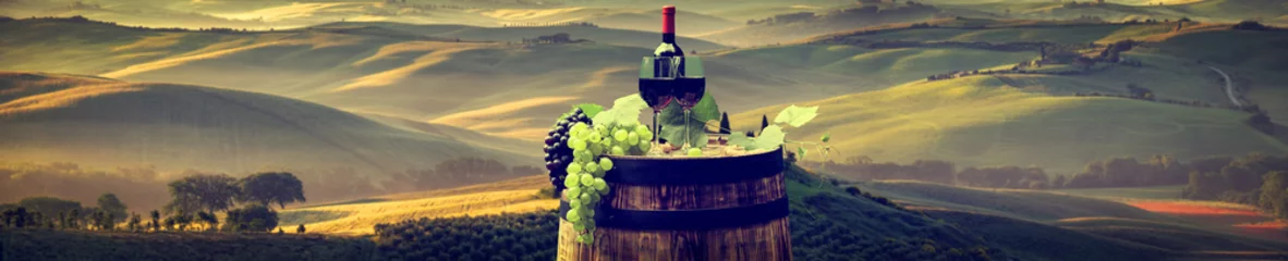 Fotobehang Red wine bottle and wine glass on wodden barrel. Beautiful Tuscany background © ZoomTeam