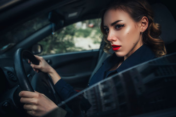 Plakat Beautiful brunette sexy spy agent (killer or police) woman in leather jacket and jeans with a gun in her hand driving a car after someone, to catch him