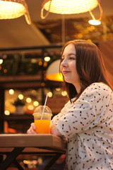 Beautiful young woman with glass of orange juice sitting at kitchen table. Photo with idea healthy food