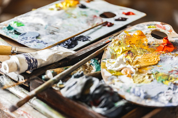 Palette with mix of colors brushes and paints close-up