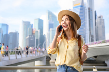 Young woman in calling on phone with friend during travel in Singapore