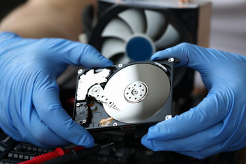 Hdd pc repair service concept. Male hand in blue protective gloves hold silver hdd and install pc...