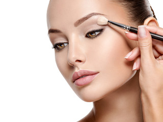 Beautiful woman applying eyeshadow use makeup brush - obrazy, fototapety, plakaty