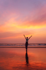 Woman with raised hands feel freedom and enjoying Goa sunset