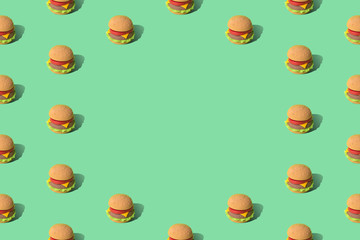 Artificial hamburger with cheese tomatoes and lettuce texture street food abstract on green.