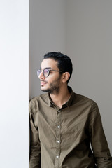 Serious or serene guy in eyeglasses looking through office window at break