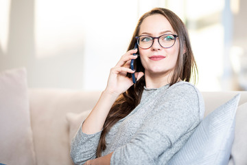 Young woman having a call while relaxing on the couch