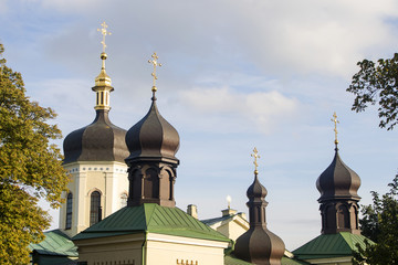 Fototapeta na wymiar The roof of a multi-domed Orthodox church with black domes crowned with gilded crosses