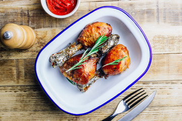 Grilled chicken drumstick bbq with rosemary on a rustic wooden background.
