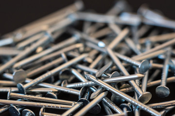 metal construction nails close-up on black background - obrazy, fototapety, plakaty