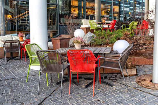 Multi-colored chairs and wooden tables in an outdoor cafe