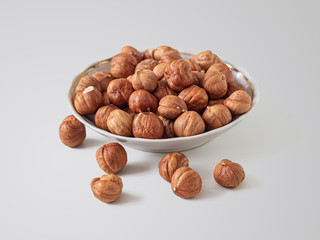 Hazelnuts in a small plate on a light background