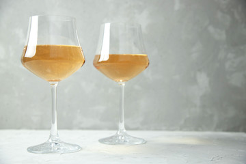Orange wine in two glass glasses on a gray table and a gray background. Copy space.