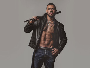 Brutal attractive bearded biker man with tattooed poses in black jacket. Copy space. Handsome...