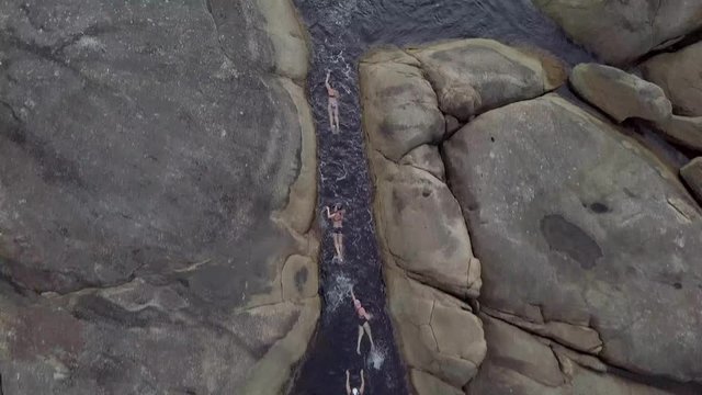 Plano de drone con grupo de personas nadando en el mar cerca de una playa de agua cristalina 4K