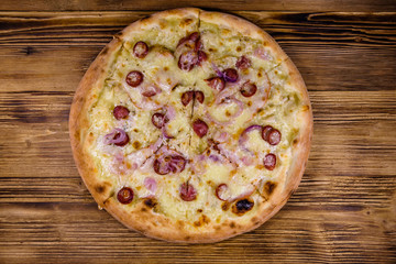Pizza with sausages, ham and parmesan cheese on a wooden table. Top view