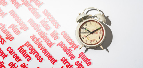 the alarm clock on color surface with written words around it for your motivation succes, start to move