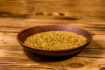 Ceramic plate with fenugreek seeds on wooden table
