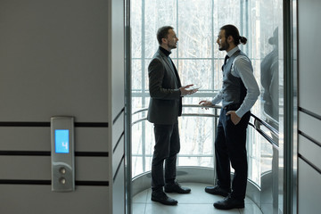 Two elegant businessmen discussing working points or terms of agreement