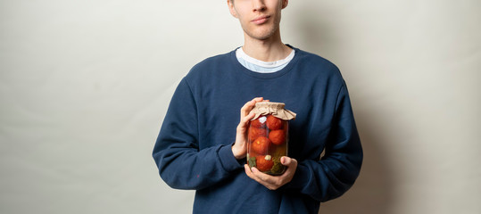 a man holding a homemade  jar with pickled vegetables isolated against the color wall