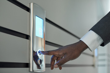 Hand of young African businessman in formalwear pushing elevator call button