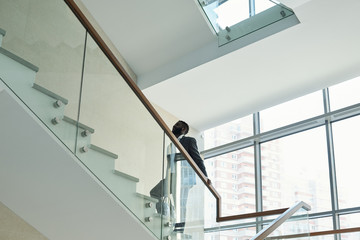 Young contemporary African businessman in elegant suit going upstairs