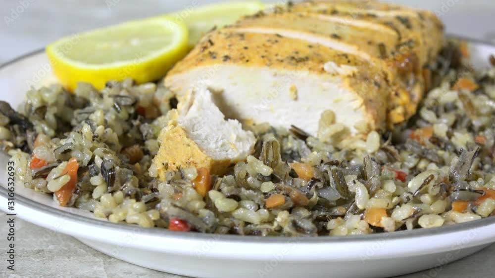 Wall mural eating a forkful of wild rice with rosemary chicken on a plate