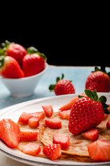 Pancakes with fresh strawberry on a blue wooden background