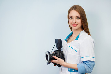 Fototapeta premium Image of a woman doctor isolated over white wall background. Dentist with a camera in hand. Copy space. Beautiful girl in a white coat