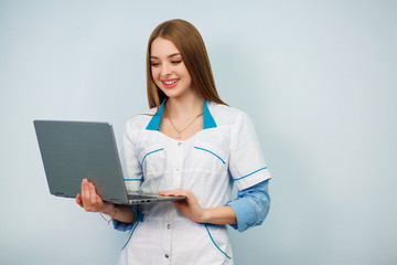 Happy female doctor using tablet computer isolated on a white background. Beautiful girl in a white coat. Copy space