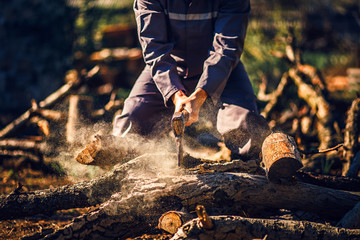 Man holding an industrial ax. Ax in hand. A strong man holds an ax in his hands against the background of chainsaws and firewood. Strong man lumberjack with an ax in his hand. Chainsaw close up.