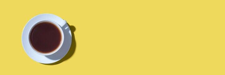 A cup of black coffee or tea on a yellow background. Minimal concept. Flat lay, top view.