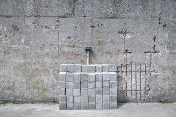 Stones and a hammer in front of a damaged stone wall