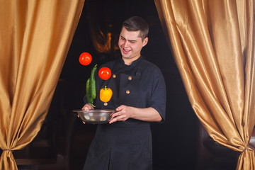 Chef throws up fresh vegetables. Funny photo. Copy space. Portrait of a cook at work.