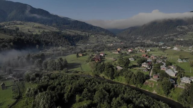 Scenic panoramic view of picturesque mountain valley in summer. Beautiful view ofn mountain village between forests and slopes.