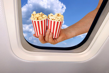 male hand holds two cups with popcorn on a background of a beautiful heavenly landscape of blue sky...