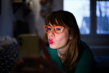 Hipster girl with glasses looking at her mobile phone