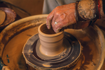 The master forms a clay cup on a potter's wheel. A potter's hands preparing a clay pot. Close-up.