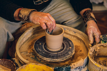 The master forms a clay cup on a potter's wheel. A potter's hands preparing a clay pot. Close-up.