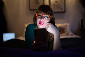 Obraz premium Hipster girl with glasses looking at her mobile phone