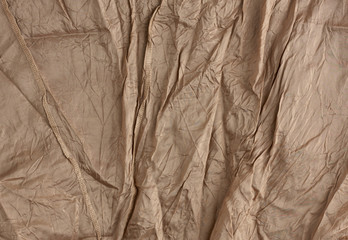 texture of crumpled brown synthetic fabric with seams for sewing clothes