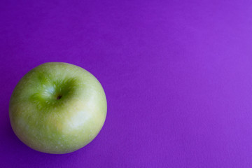 Green apples on purple background. Color trends concept with copy space