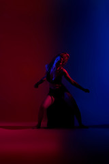 Black dressed and braided hair woman dancing on a blue and red background.